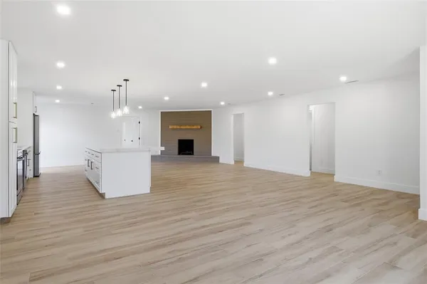 a view of an empty room with kitchen stove and wooden floor