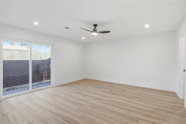 an empty room with wooden floor and fan