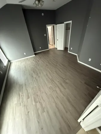 a view of an empty room with wooden floor and a window