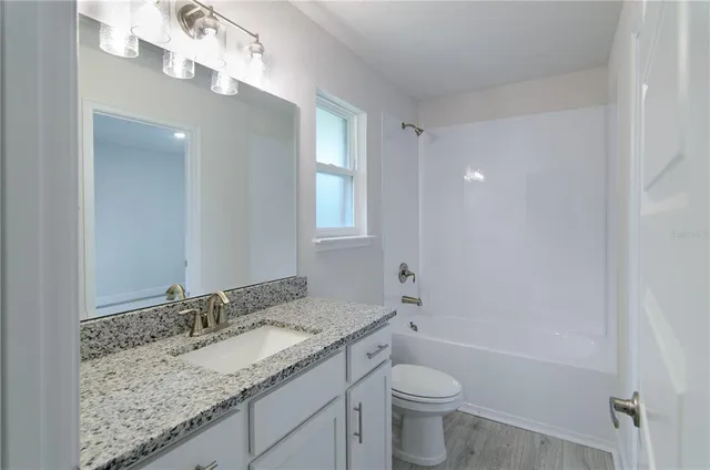 a bathroom with a granite countertop sink a toilet and a mirror