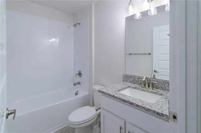 a bathroom with a granite countertop sink a toilet and shower