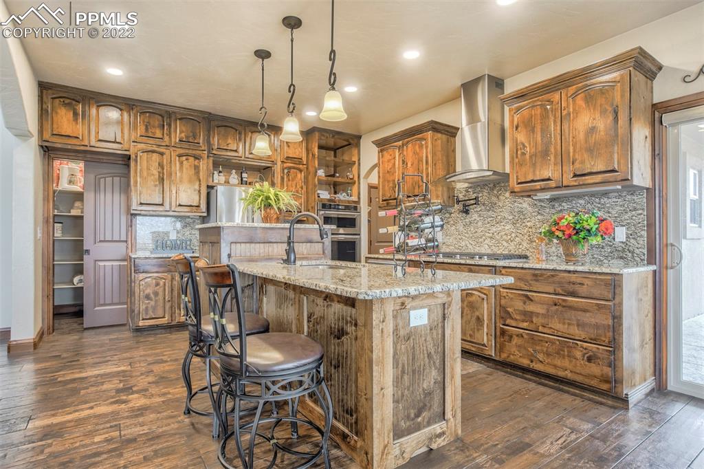 14335 Jones Road Peyton, CO 80831 - Photo 26 of 49 a kitchen with stainless steel appliances kitchen island granite countertop a table chairs and a refrigerator