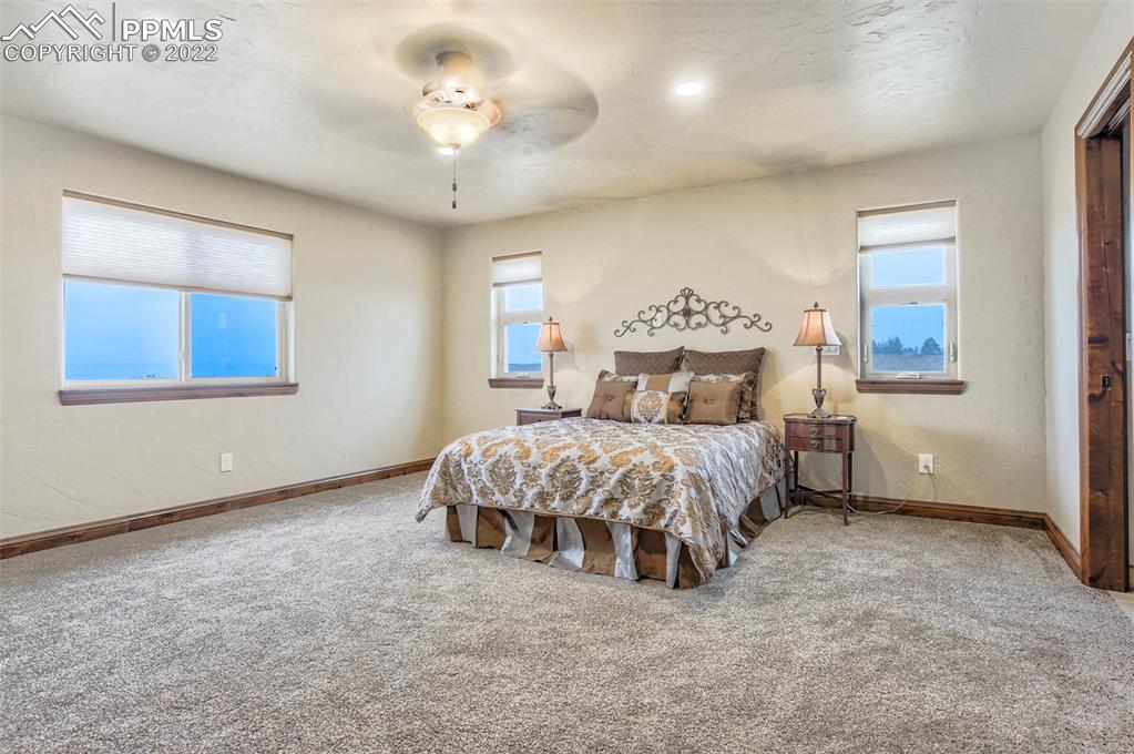14335 Jones Road Peyton, CO 80831 - Photo 37 of 49 a spacious bedroom with a bed and a chandelier