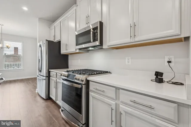 a kitchen with stainless steel appliances granite countertop white cabinets and a stove top oven