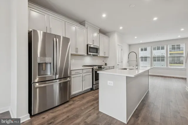 a kitchen with kitchen island stainless steel appliances a refrigerator sink and microwave