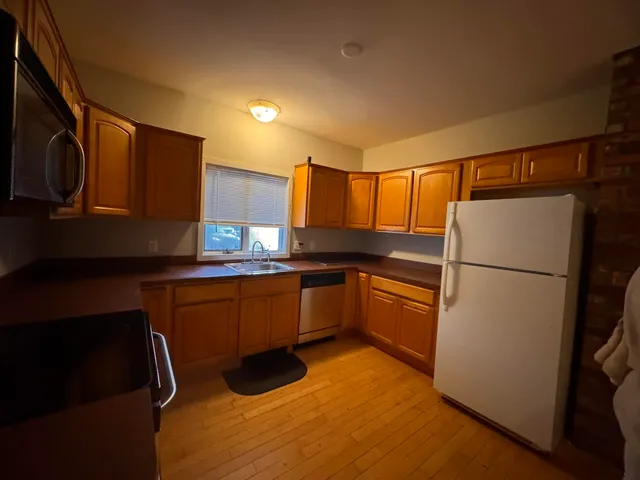 a kitchen with granite countertop stainless steel appliances a refrigerator a sink a stove top oven and cabinets