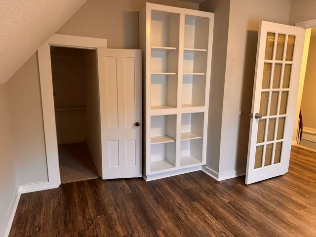 a view of an empty room with wooden floor and closet