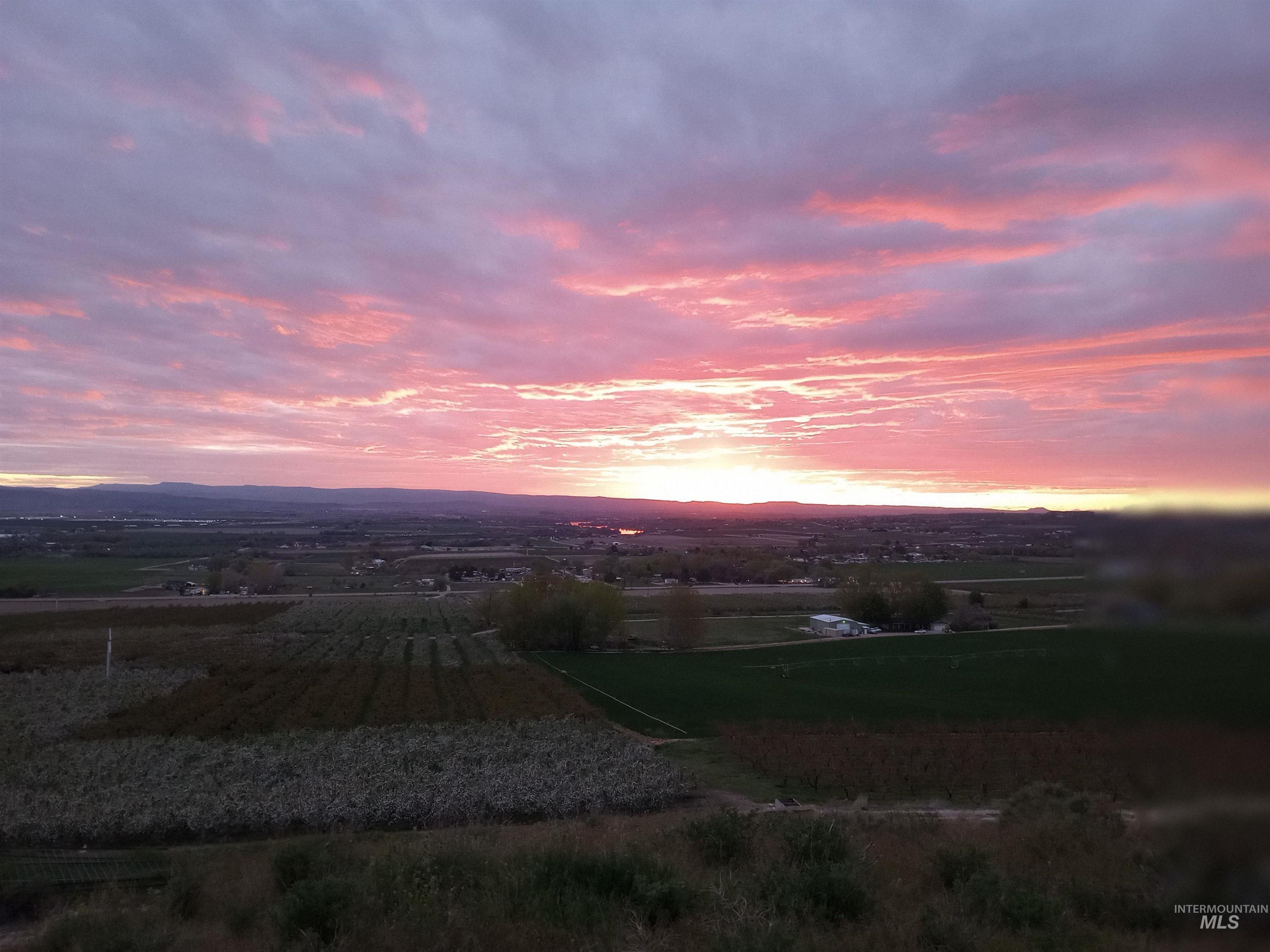 14526 Perfection Lane Caldwell, ID 83607 - Photo 3 of 47 Expansive landscape featuring distant mountains and a vibrant pink and orange sunset
