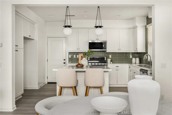 a kitchen with white cabinets stainless steel appliances and dining table