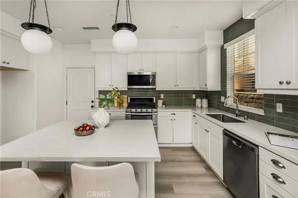 a kitchen with granite countertop a sink stainless steel appliances and cabinets
