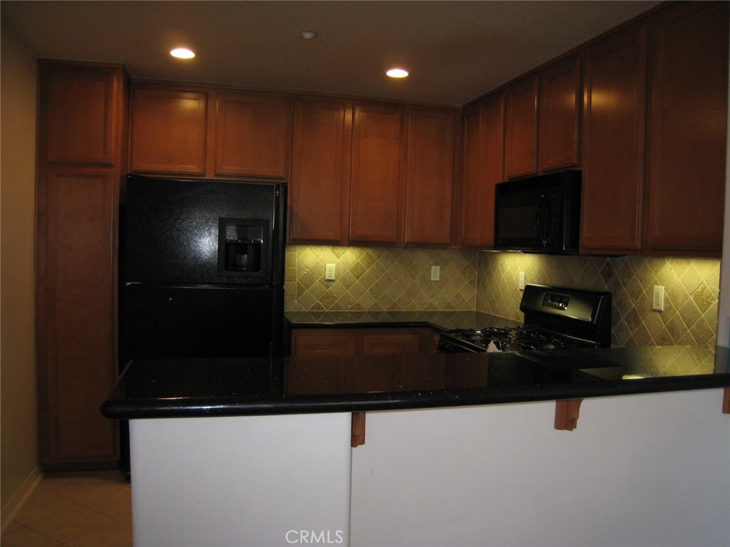 216 Dewdrop Irvine, CA 92603 - Photo 6 of 14 a kitchen with stainless steel appliances wooden cabinets and a counter top space