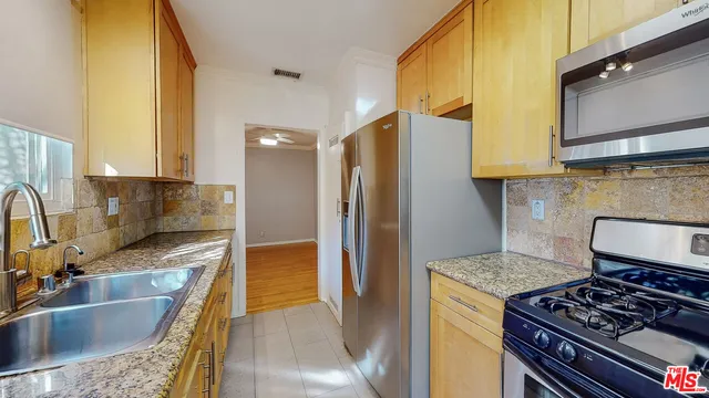 a kitchen with granite countertop a sink a stove and refrigerator