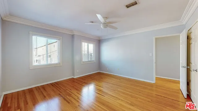 a view of empty room with wooden floor and fan