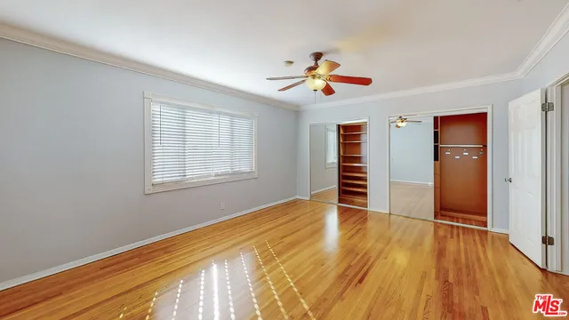 a view of empty room with wooden floor and fan