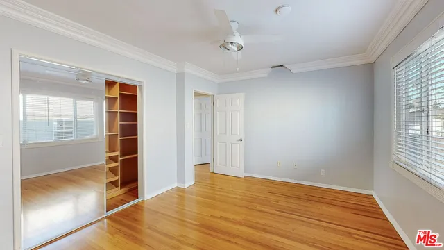 a view of empty room with wooden floor and fan