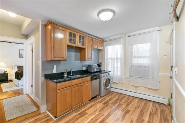 a kitchen with stainless steel appliances granite countertop a stove a sink and white cabinets with wooden floor