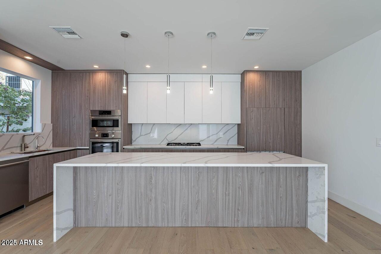 2130 East Turney Avenue, Unit 4 Phoenix, AZ 85016 - Photo 2 of 15 a view of a kitchen with kitchen island a sink wooden floor and a counter top space