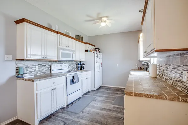a kitchen with granite countertop white cabinets and white appliances