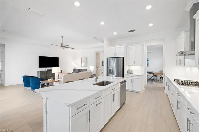 a large white kitchen with a stove a sink a refrigerator and a flat screen tv