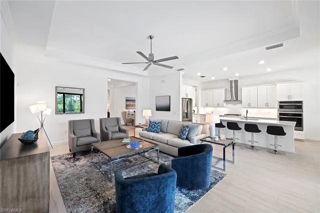 a living room with furniture kitchen view and a large window
