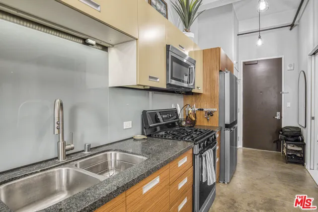 a kitchen with stainless steel appliances granite countertop a sink a stove and a refrigerator