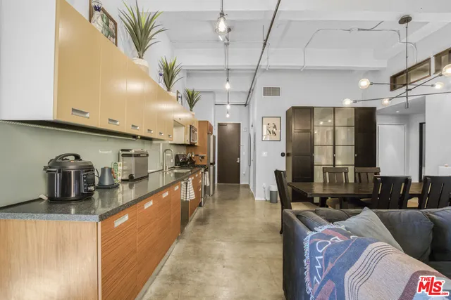 a kitchen with stainless steel appliances kitchen island granite countertop a refrigerator a stove and a sink with wooden floor