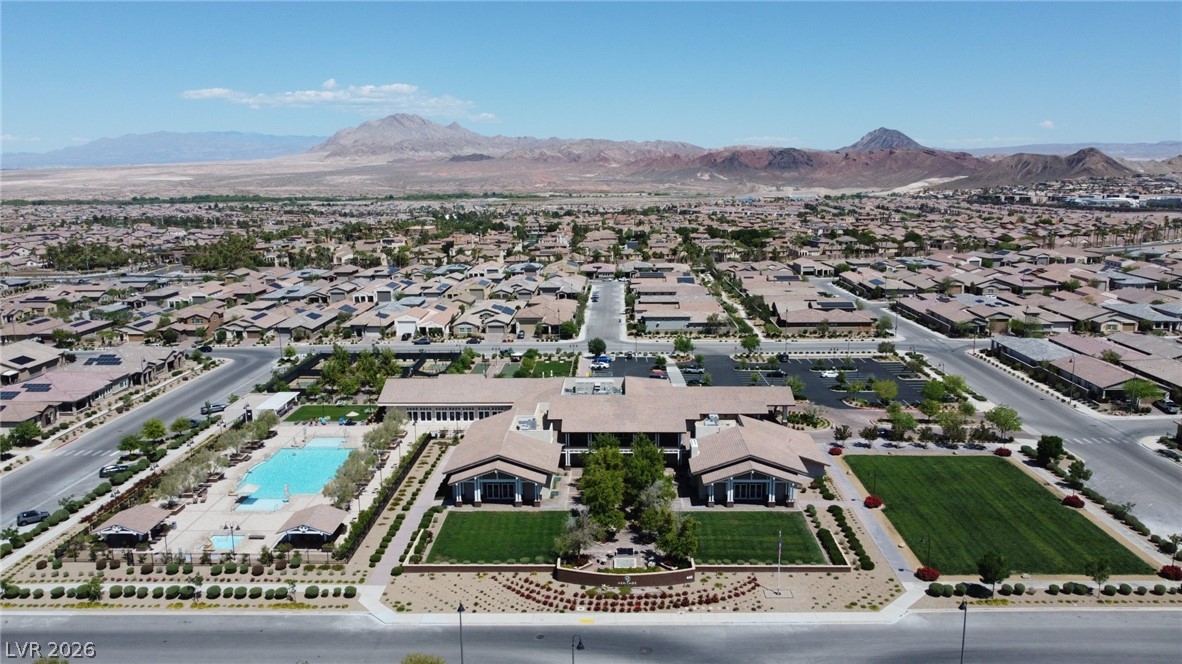 498 Pebble Run Avenue Henderson, NV 89011 - Photo 31 of 47 An aerial perspective reveals a vibrant community hub with inviting pool, recreation facilities, and manicured landscaping, all set against a distant mountain range.