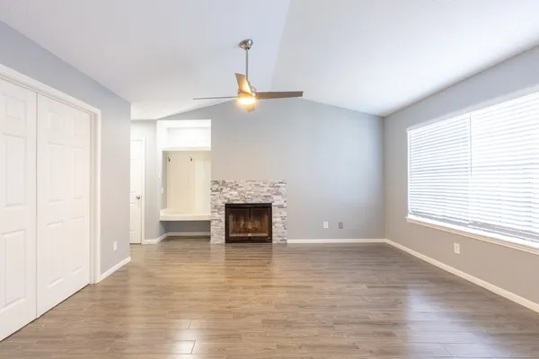 an empty room with wooden floor fireplace and windows