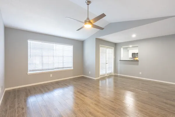 a view of an empty room with wooden floor and a window