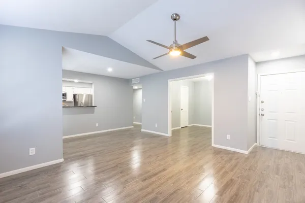 a view of an empty room with window and wooden floor