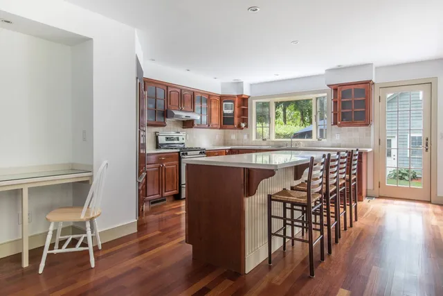 a kitchen with stainless steel appliances granite countertop table chairs stove and wooden floor