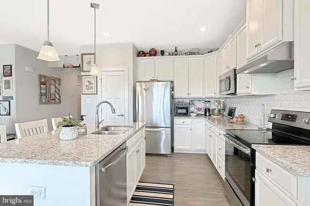 a kitchen with stainless steel appliances granite countertop a sink a stove and a refrigerator