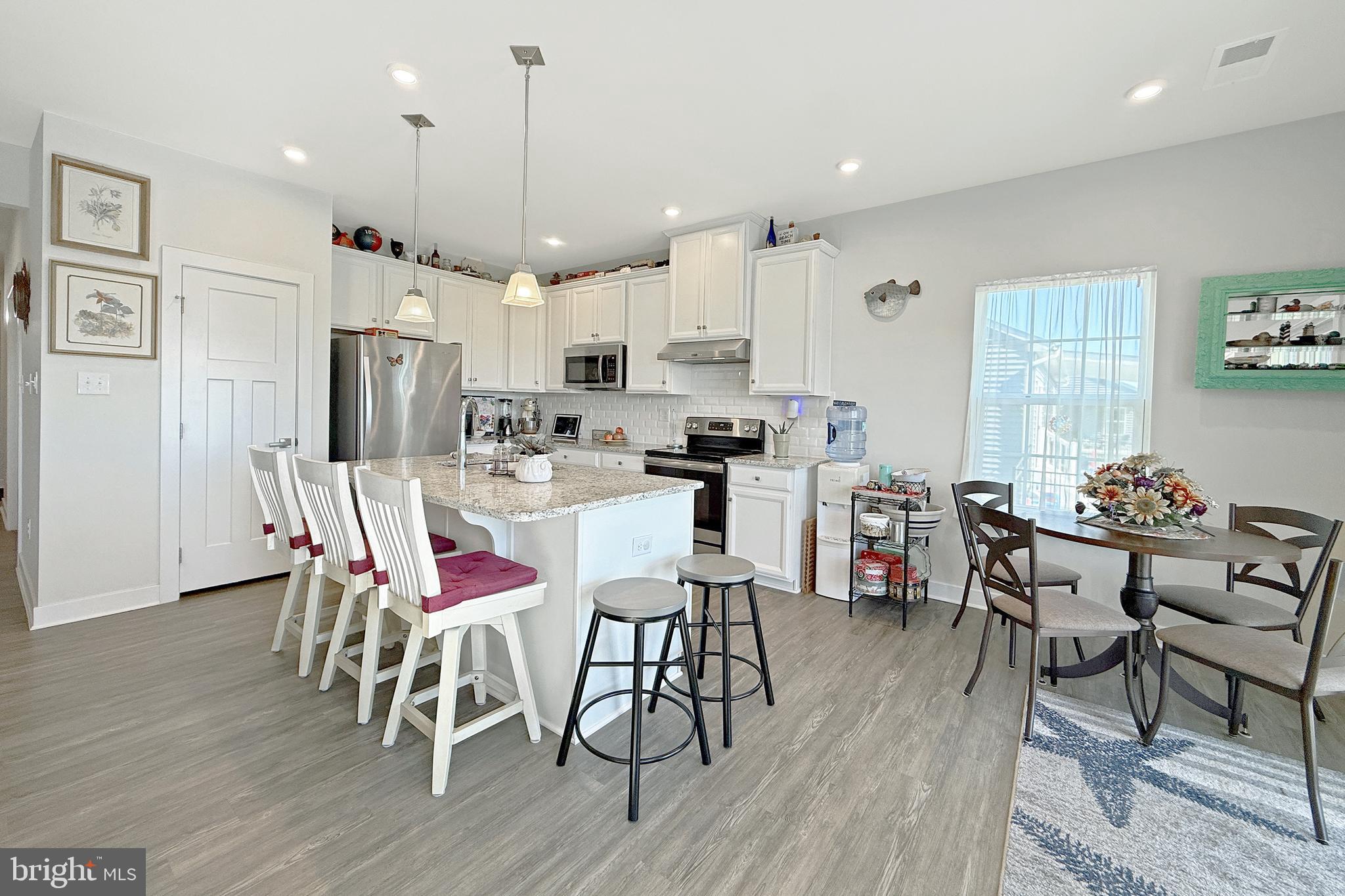 24901 Long Cove Court Millsboro, DE 19966 - Photo 5 of 23 a dining room with stainless steel appliances kitchen island granite countertop a dining table chairs and a refrigerator