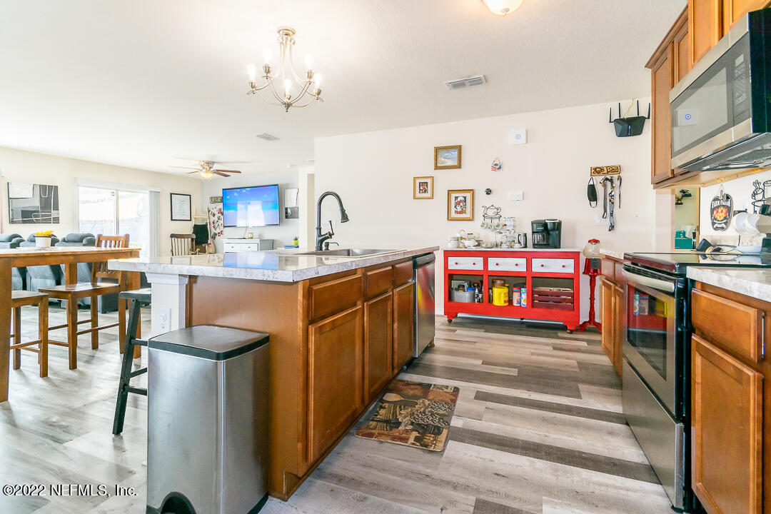 3807 Bronco Road Middleburg, FL 32068 - Photo 17 of 25 a kitchen with stainless steel appliances kitchen island granite countertop a sink dishwasher a stove and a dining table with wooden floor