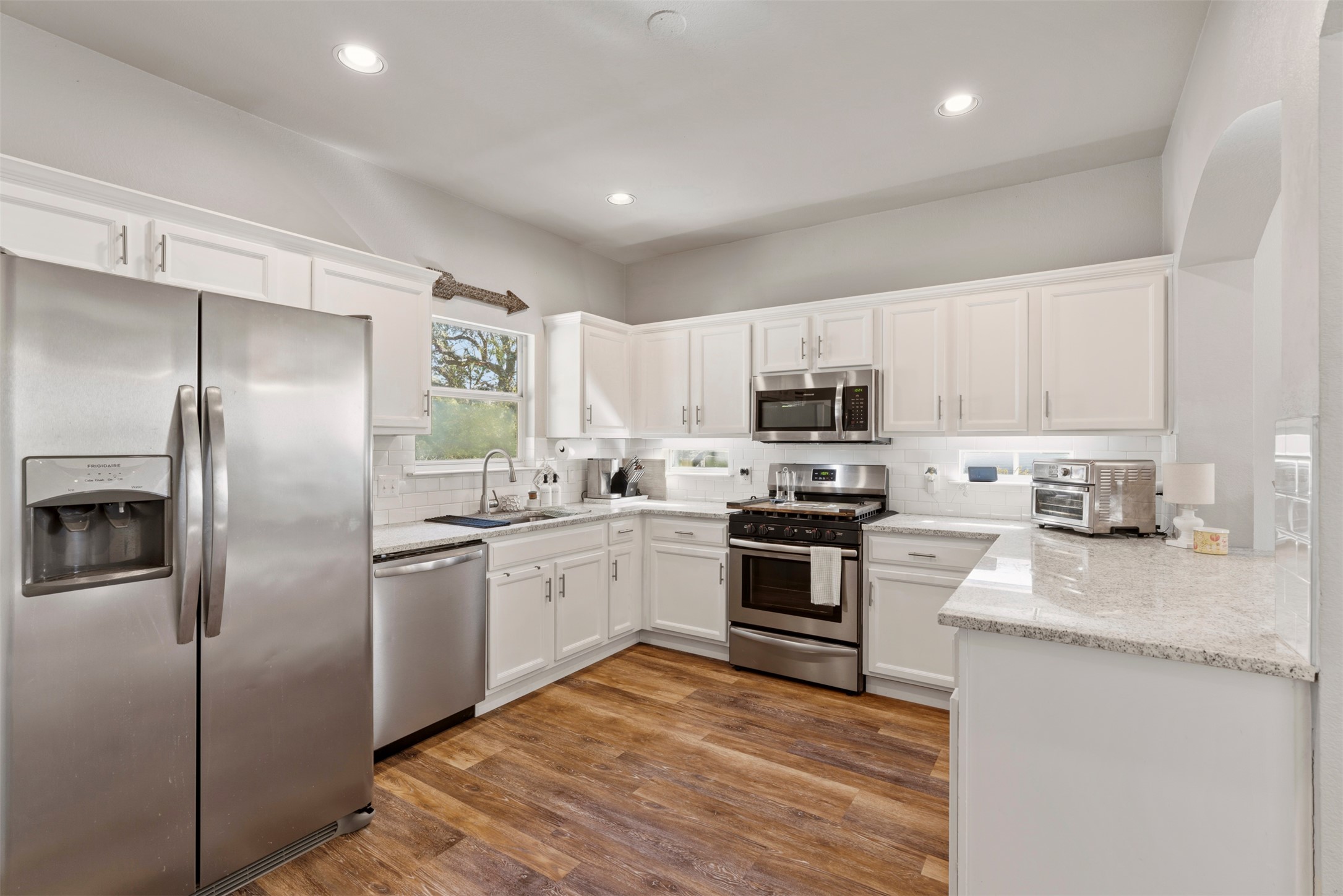 913 Bogart Road Cedar Park, TX 78613 - Photo 8 of 27 Kitchen featuring stainless steel appliances, white cabinetry, dark wood finished floors, light stone counters, and recessed lighting