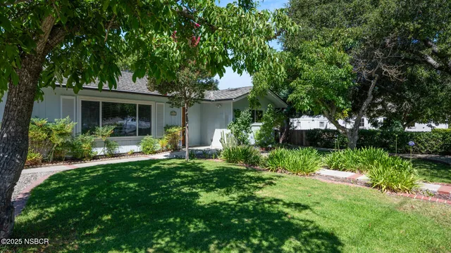 a front view of a house with a yard and potted plants