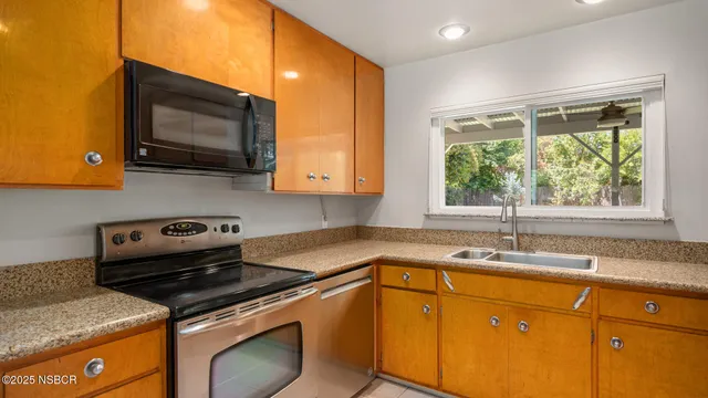 a kitchen with granite countertop a sink a stove top oven and cabinetry