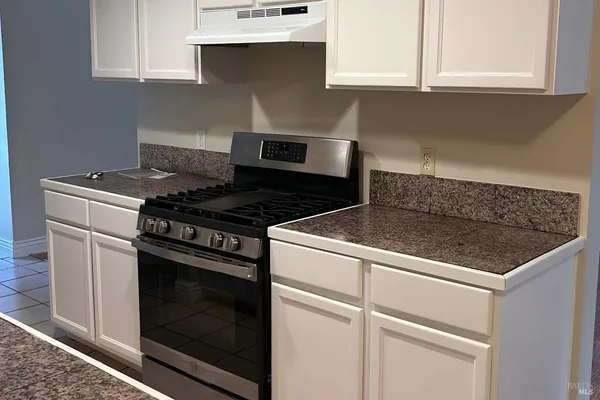 a kitchen with granite countertop a stove and a white cabinet