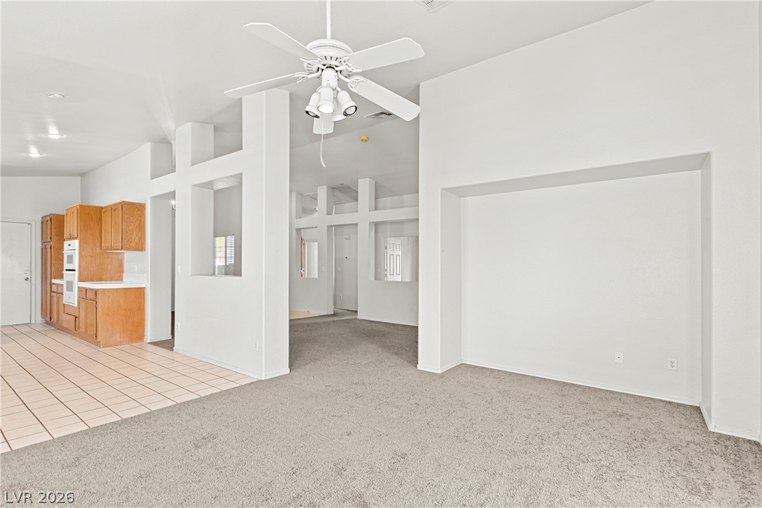 1815 Stablegate Avenue Henderson, NV 89012 - Photo 28 of 28 An open floorplan living area features plush carpeting and a kitchen with tiled floors and wooden cabinetry.