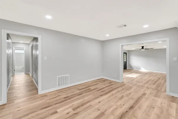 a view of an empty room with wooden floor and a ceiling fan
