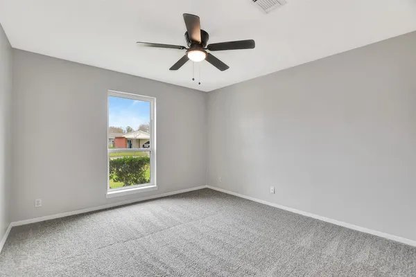 an empty room with windows and ceiling fan