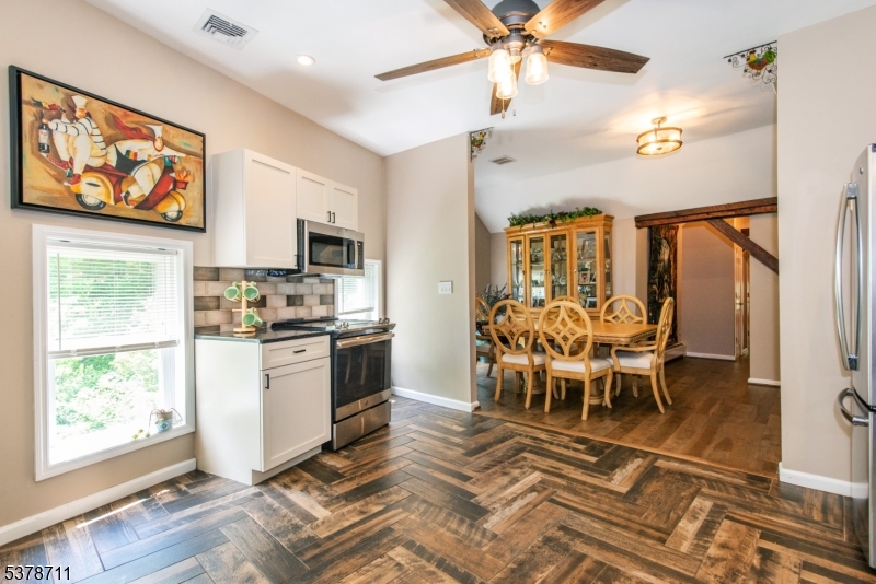 1856 Rt565, Unit 1 Glenwood, NJ 07418 - Photo 9 of 20 a kitchen with stainless steel appliances kitchen island granite countertop a refrigerator a stove a microwave oven with a dining table and chairs with wooden floor