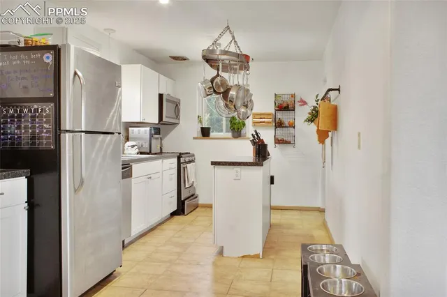 a kitchen with white cabinets and refrigerator