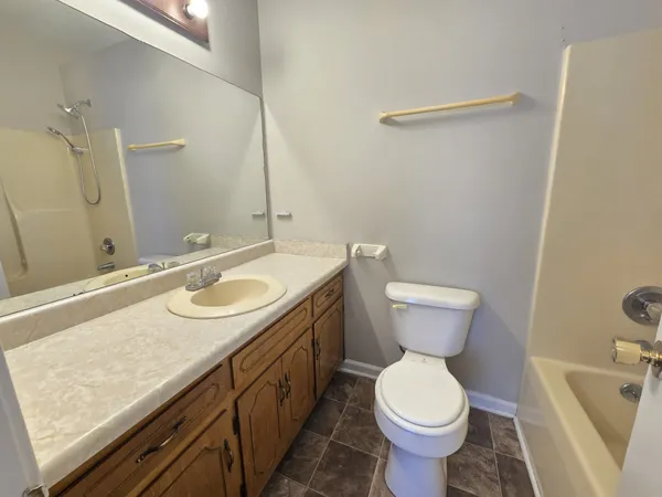 a bathroom with a granite countertop toilet sink and mirror