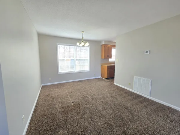 an empty room with windows and chandelier fan