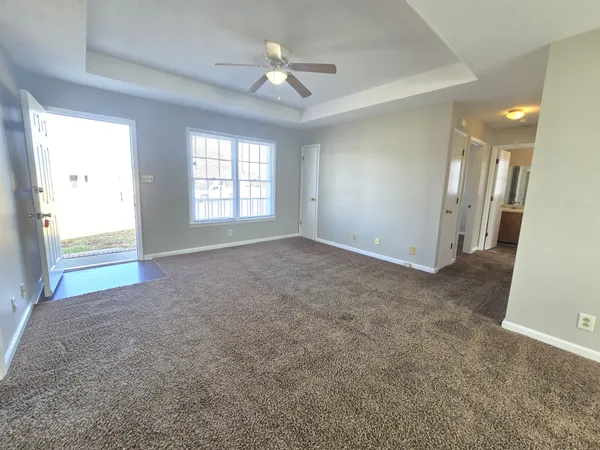 a view of a big room with windows and chandelier fan
