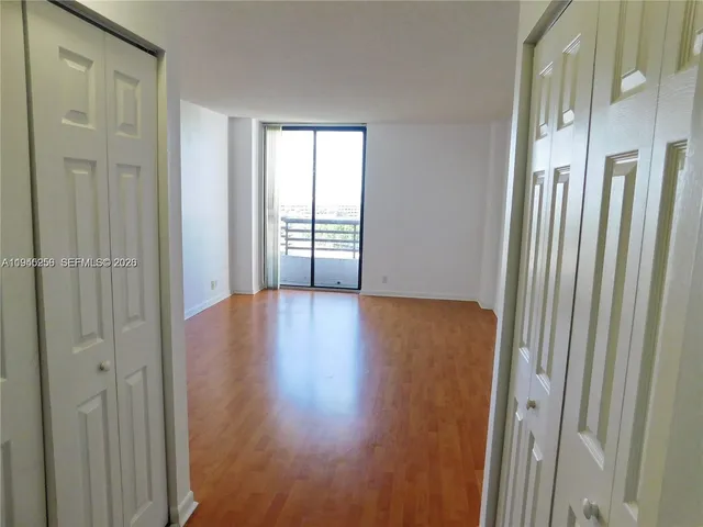 a view of a hallway with wooden floor and a window