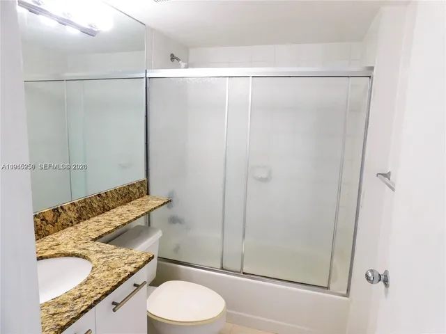 a bathroom with a granite countertop shower and a toilet