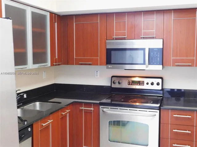 a kitchen with granite countertop a stove top oven microwave and cabinets