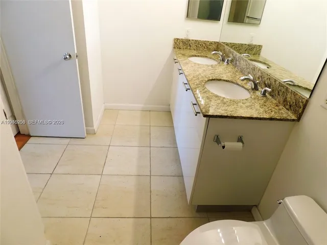 a bathroom with a granite countertop sink and a toilet
